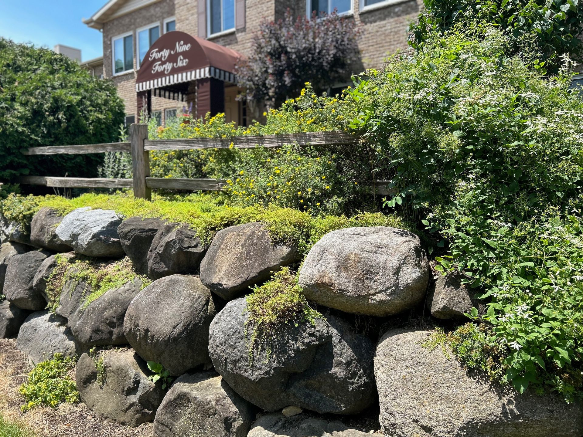A large rock wall is in front of a building.