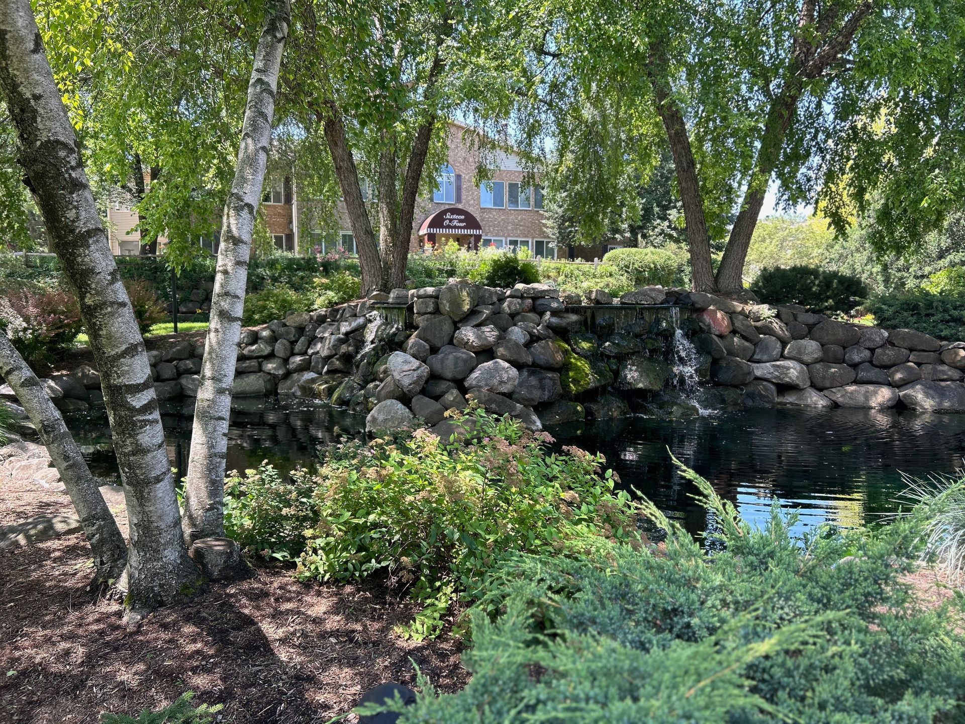 There is a waterfall in the middle of the park surrounded by trees.