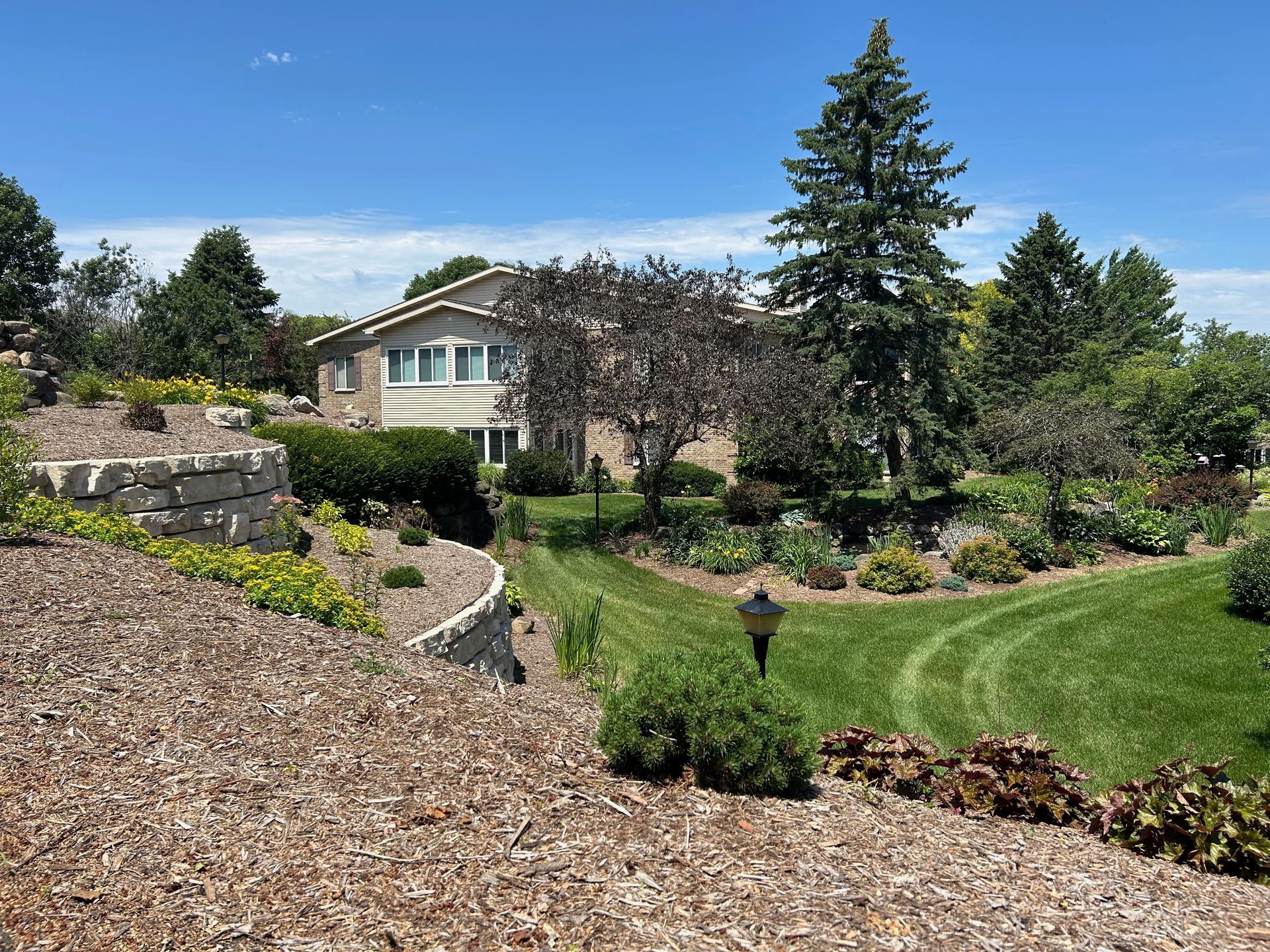 A large house is sitting on top of a lush green hillside surrounded by trees.