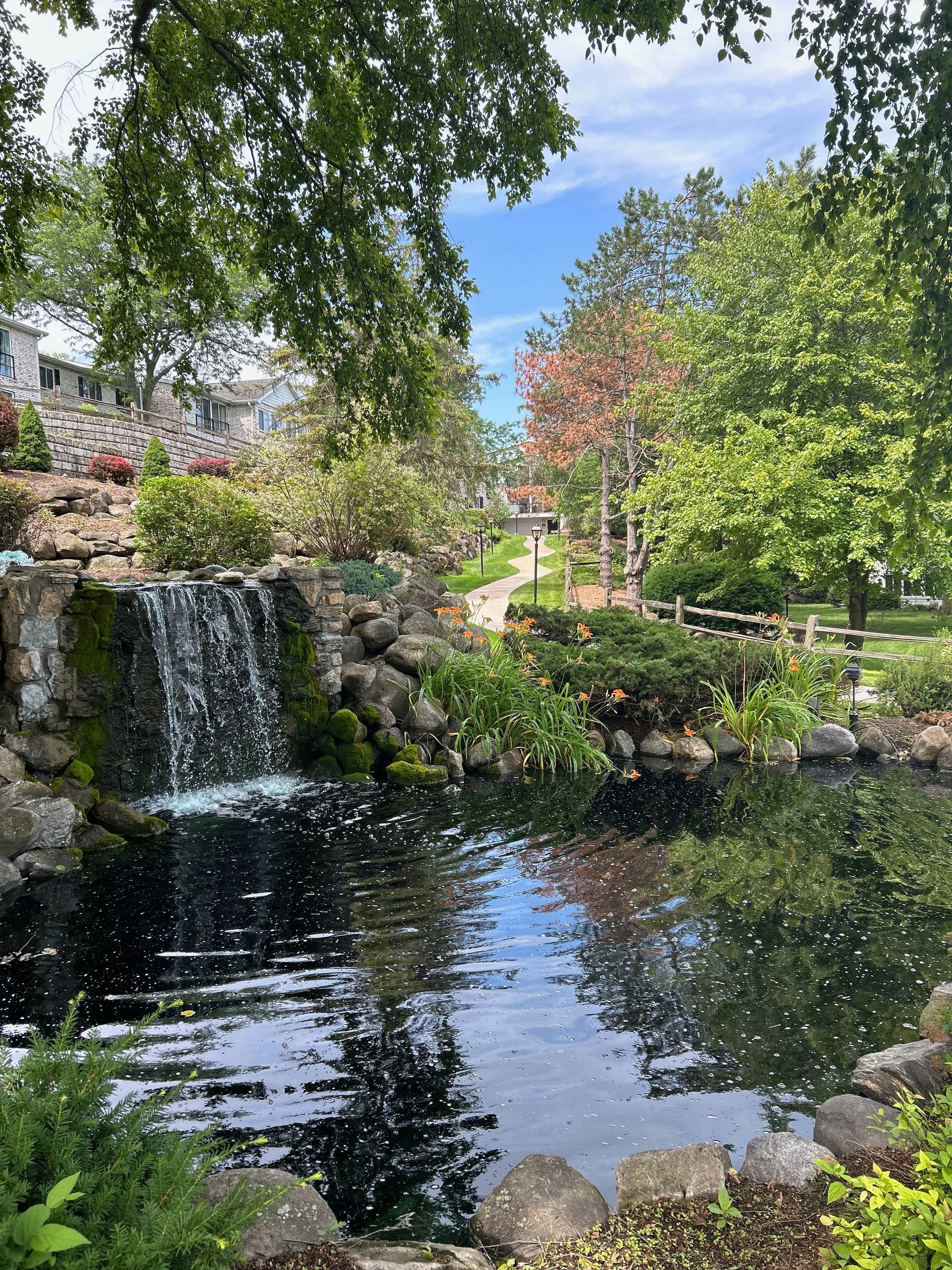 There is a waterfall in the middle of a park surrounded by trees.