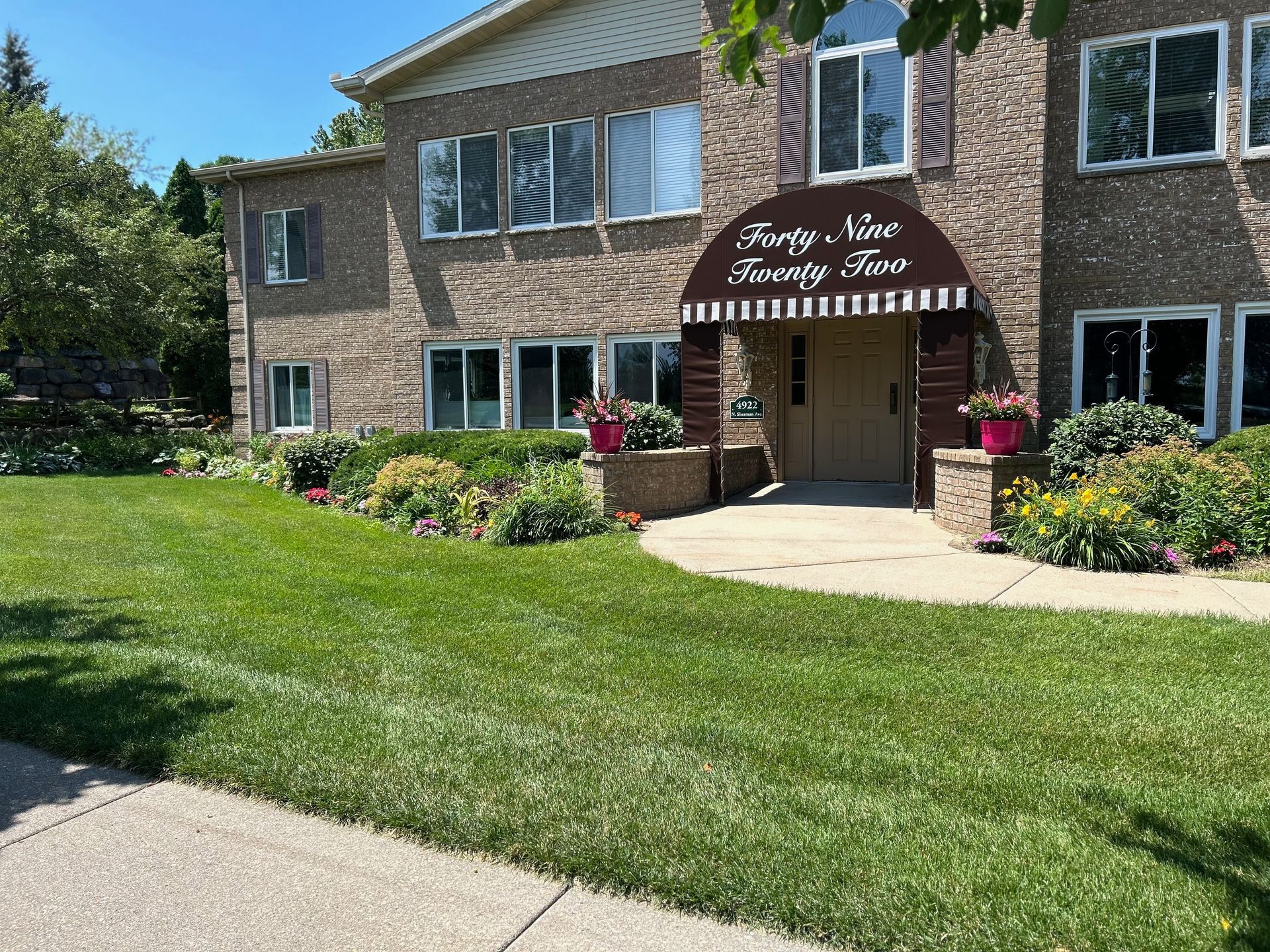 A large brick building with a large lawn in front of it.