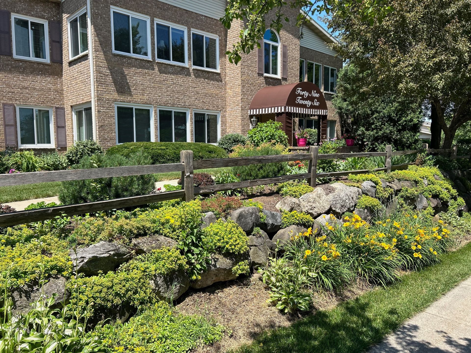 A large building with a wooden fence and flowers in front of it.