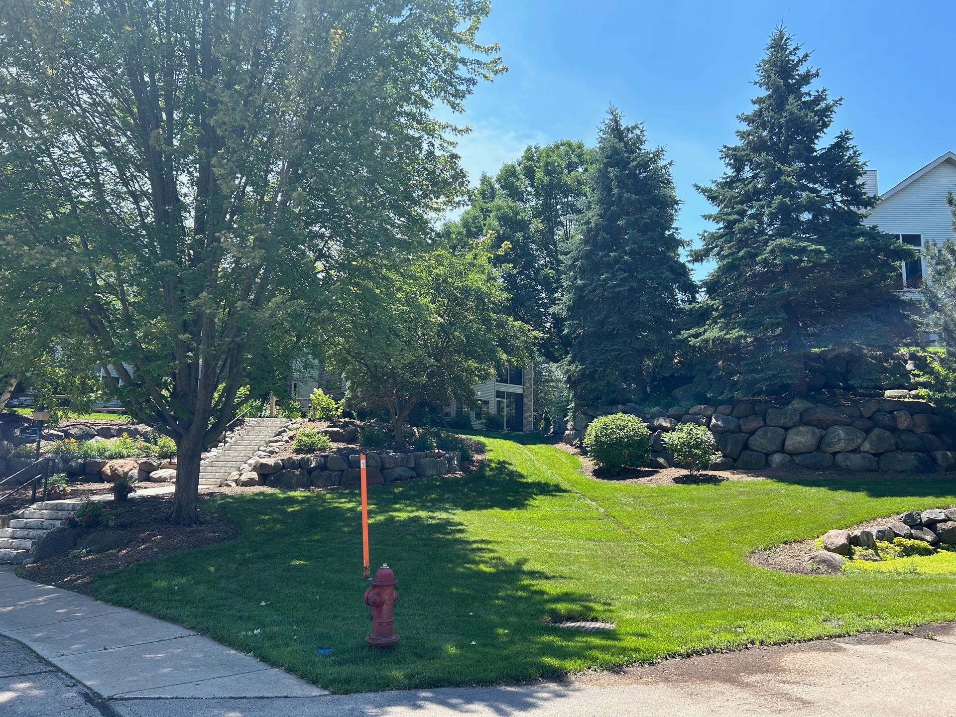 A fire hydrant is in the middle of a lush green yard.