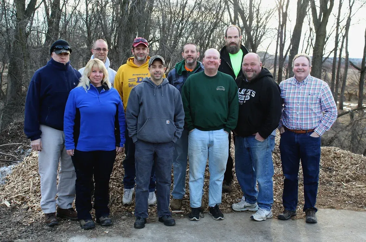 A group of people posing for a picture with one man wearing a yellow shirt that says ' team ' on it