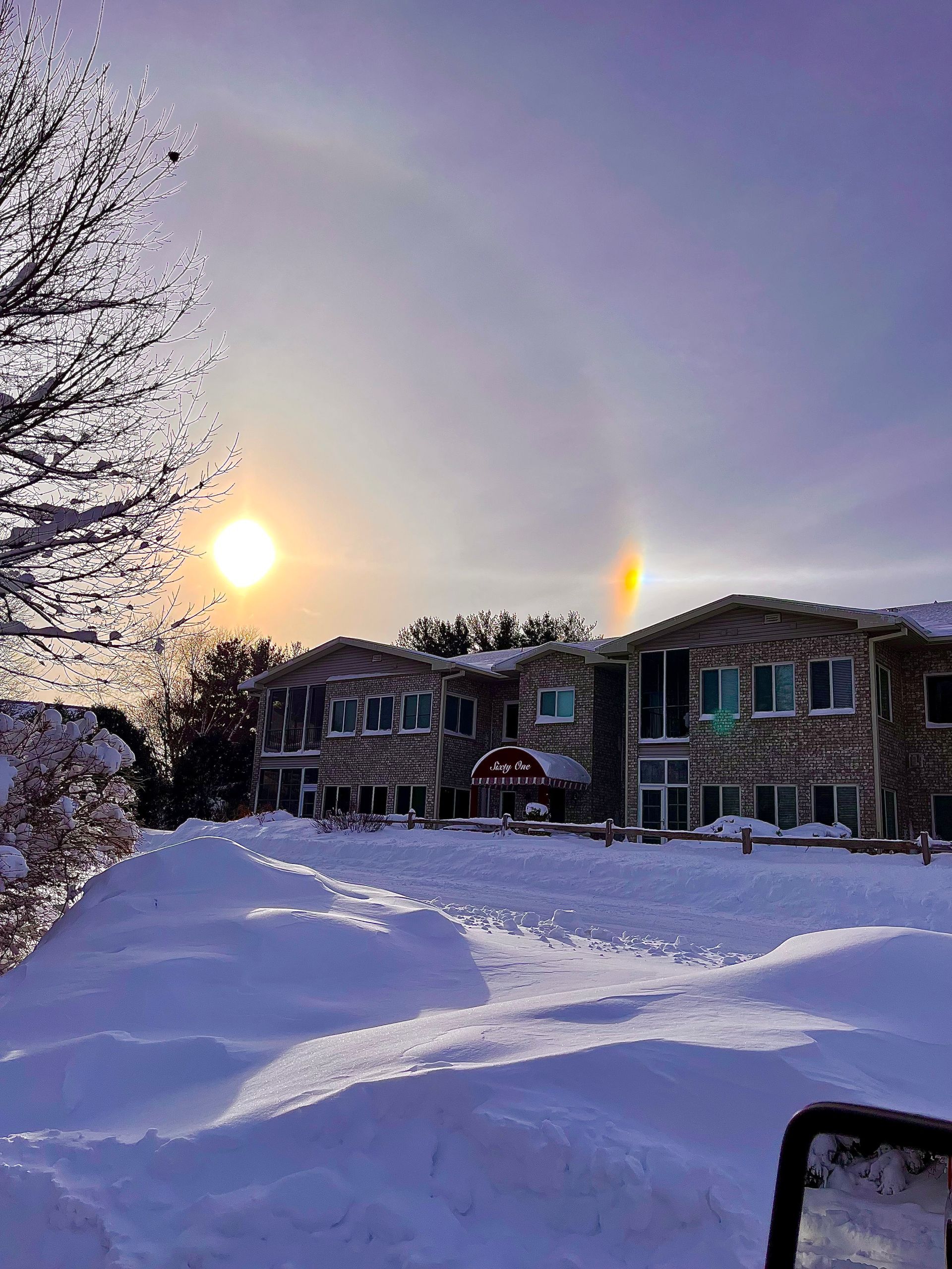 The sun is setting behind a snow covered building.
