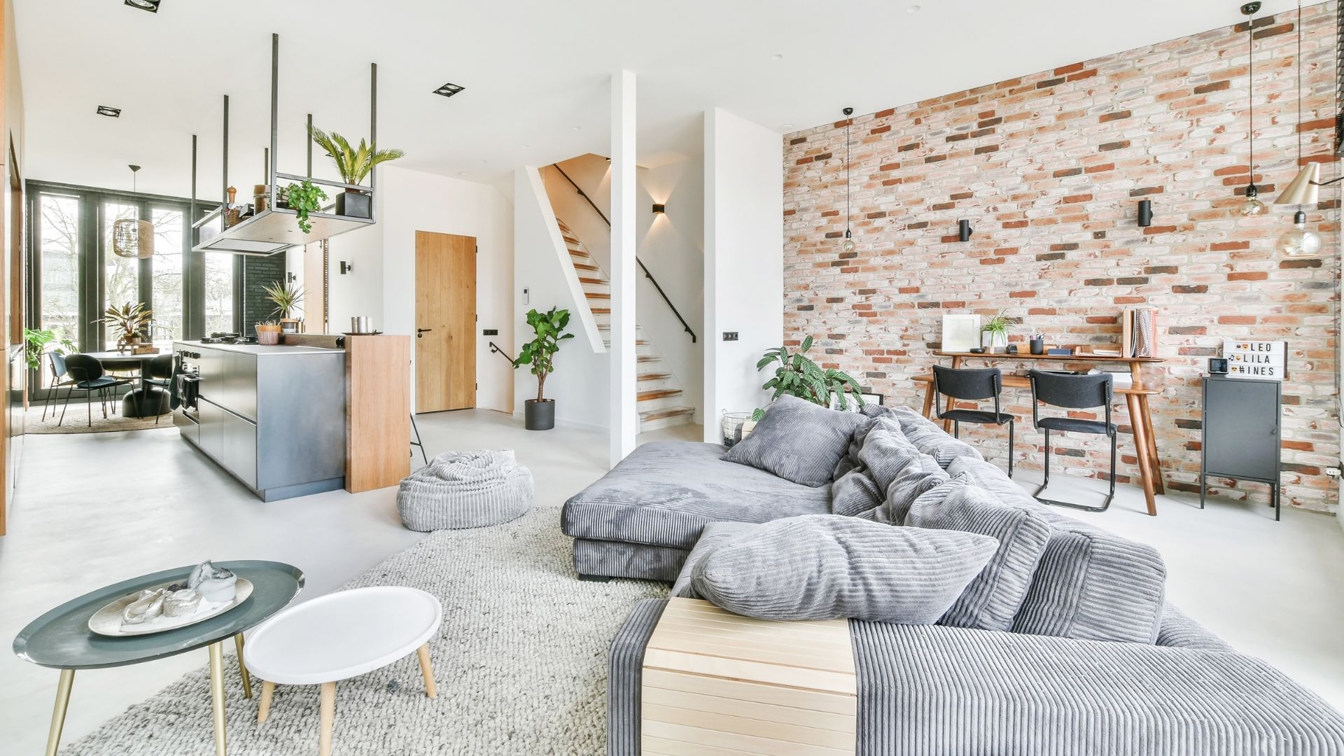 Cozy living room with grey sectional sofa, brick accent wall, and open floor plan.