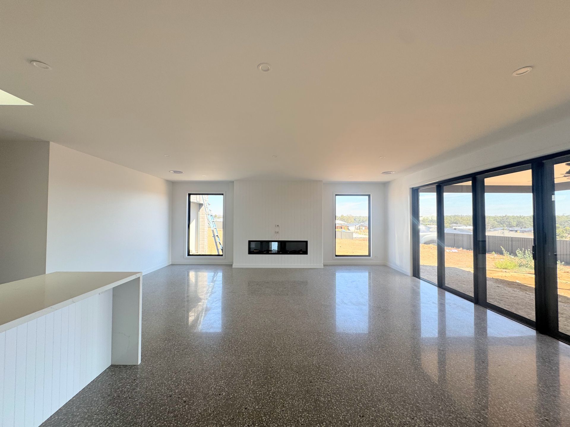 Spacious, empty living room with polished concrete floor, fireplace, and large glass doors — Crampton Painting & Decorating Pty Ltd In Maiden Gully, VIC