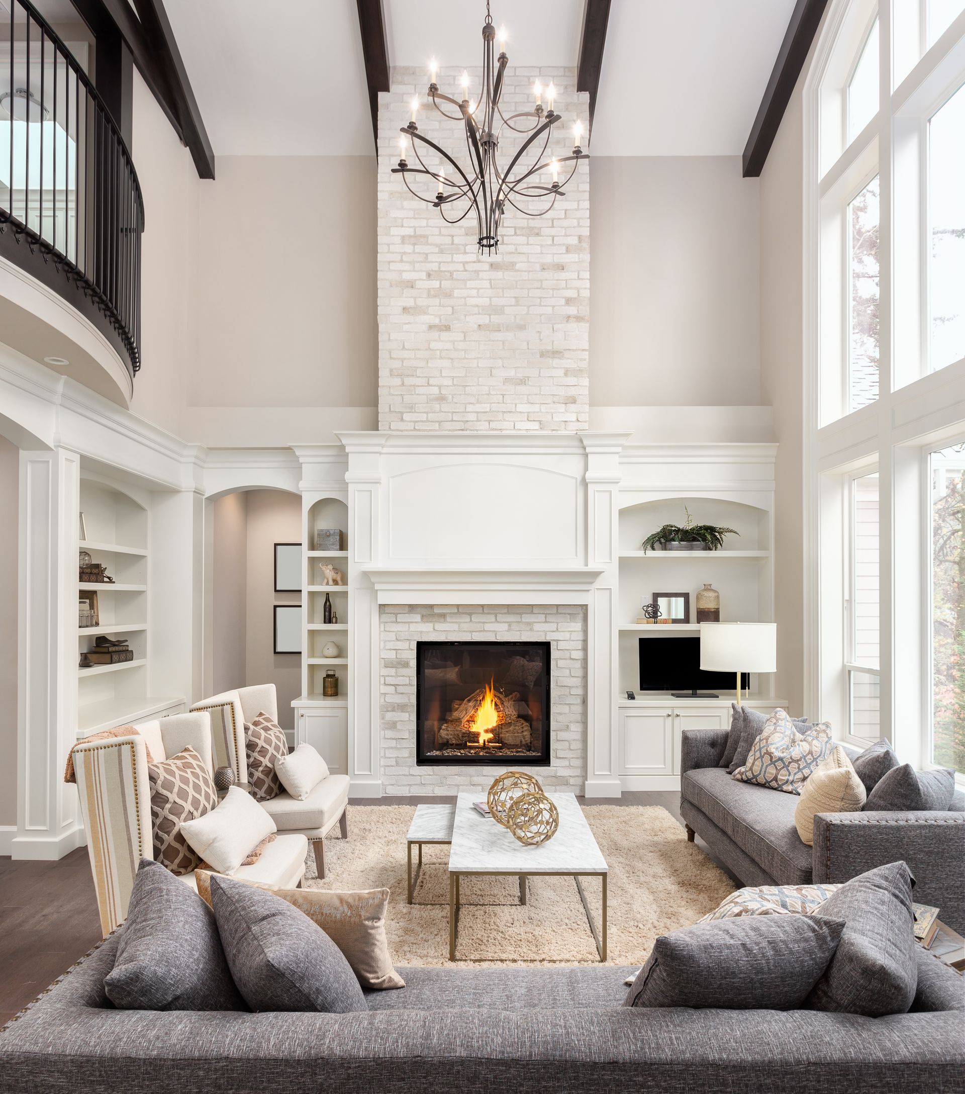 Beautiful living room interior with hardwood floors and fireplace in new luxury home. Large bank of windows hints at exterior view
