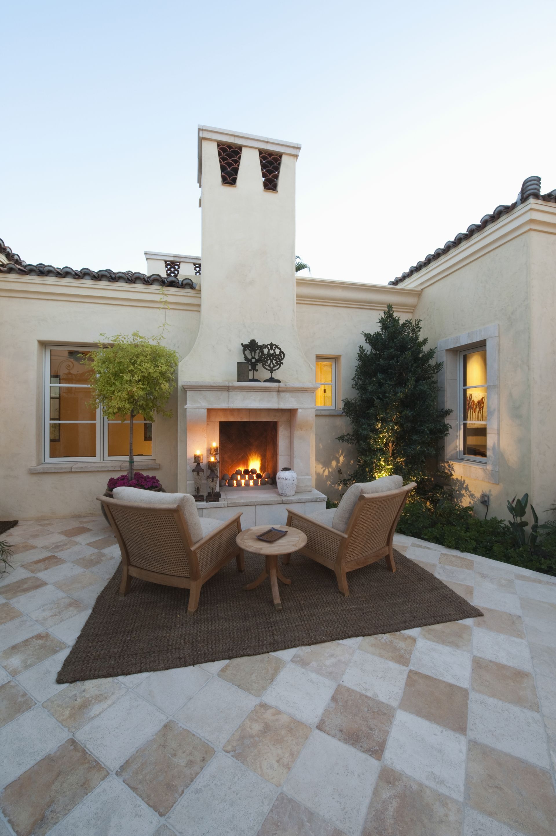 Outdoor room at dusk with fireplace and furniture.