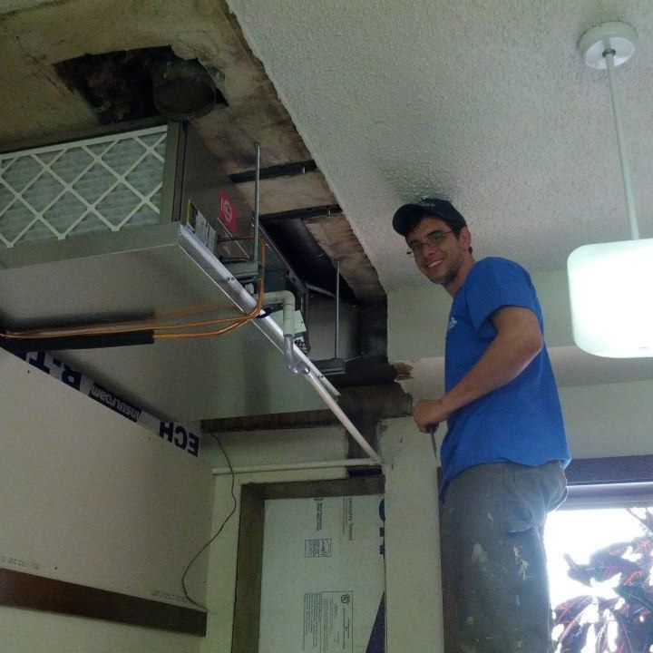 A man in a blue shirt is working on an air conditioner