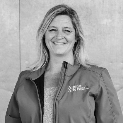 A woman is wearing a jacket and smiling in a black and white photo.