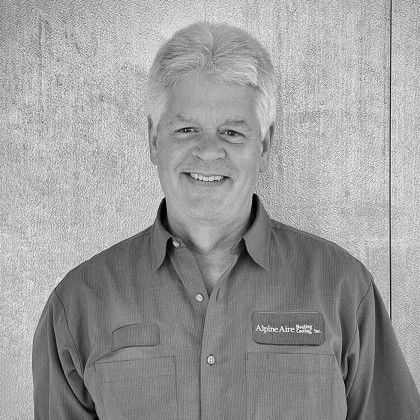 A man in a shirt is smiling in a black and white photo.