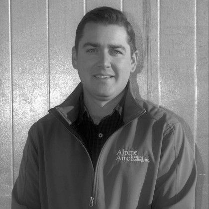 A man wearing a jacket that says aspire aire is smiling in a black and white photo.