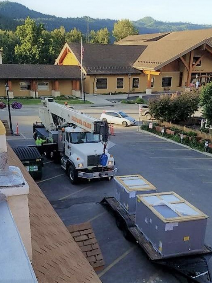 A white truck with a crane on the back is parked in a parking lot