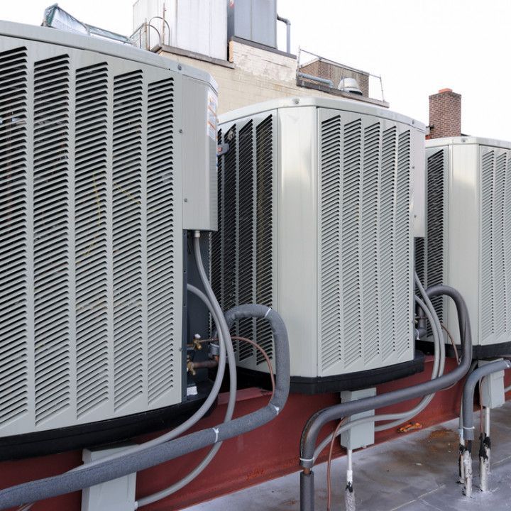 A row of air conditioners are lined up on the side of a building