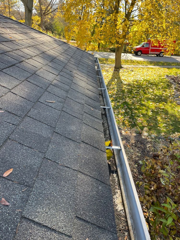 A close up of a gutter on a roof with a red truck in the background