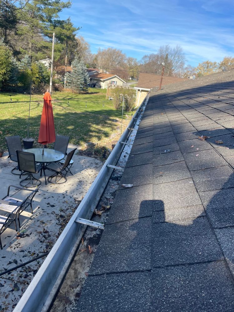 A gutter on the roof of a house with a table and chairs in the background