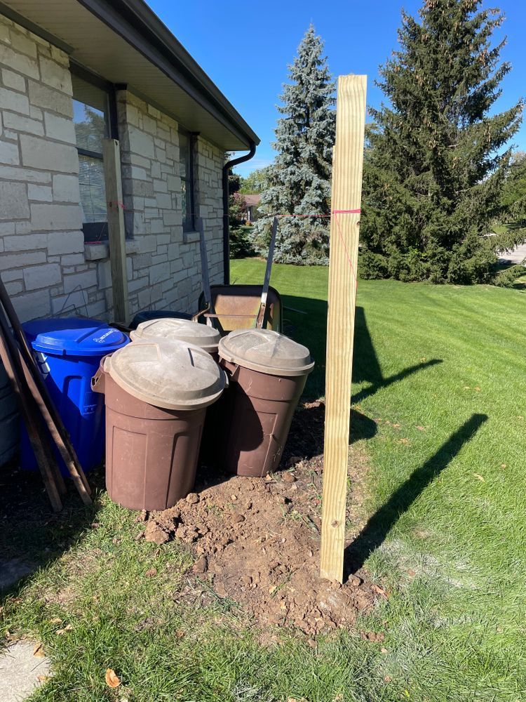 A wooden post is sitting in the dirt in front of a house