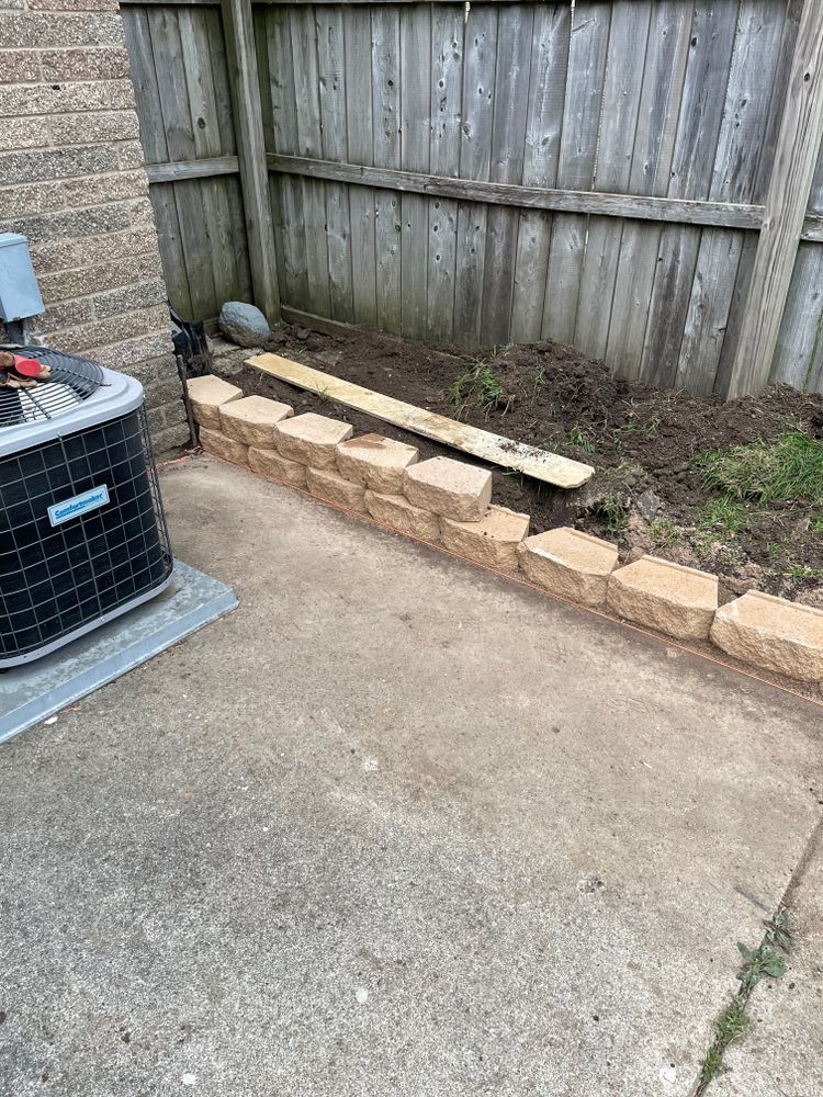 A brick wall is being built next to a wooden fence