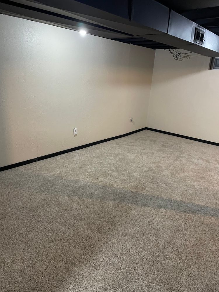 An empty basement with a carpeted floor and white walls
