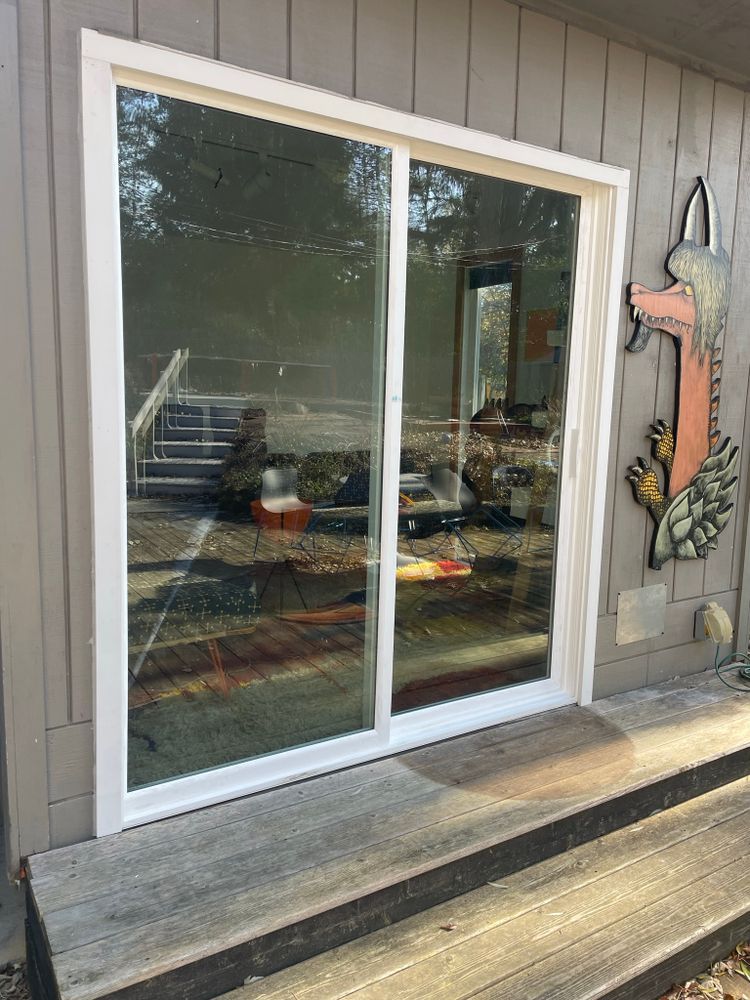 A white sliding glass door is on the side of a house