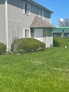 A house with a lot of grass in front of it and a water tower in the background