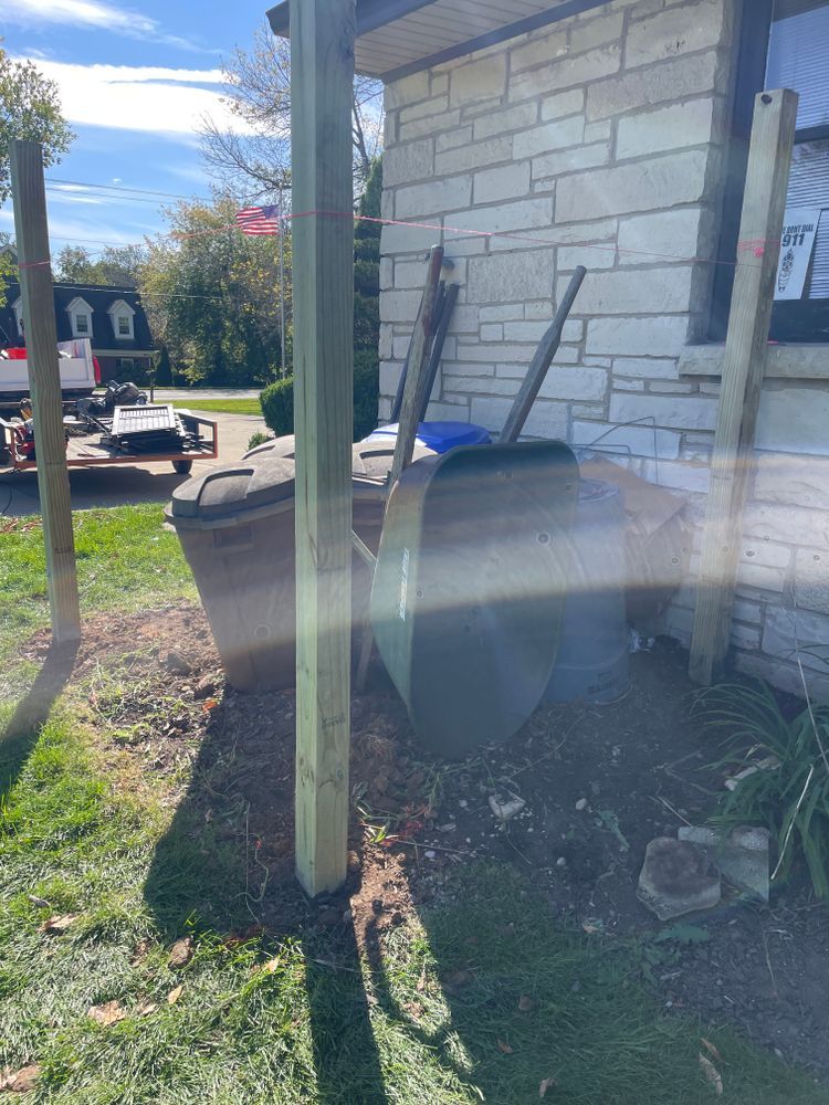 A wheelbarrow is leaning against a wooden post in front of a brick building