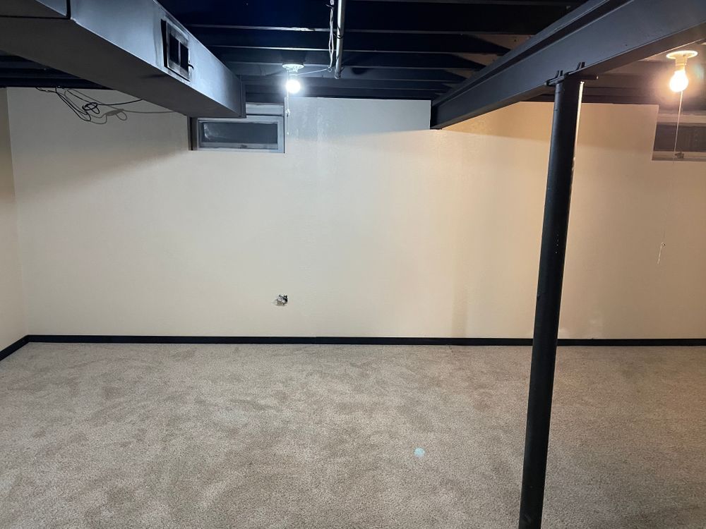 An empty basement with a black pole in the middle