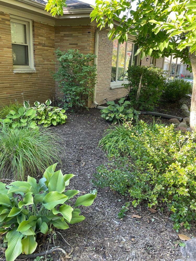 A brick house with a lush green garden in front of it