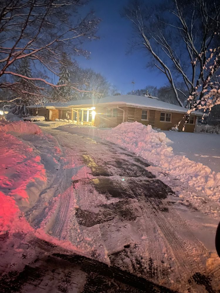 A snowy driveway in front of a house at night