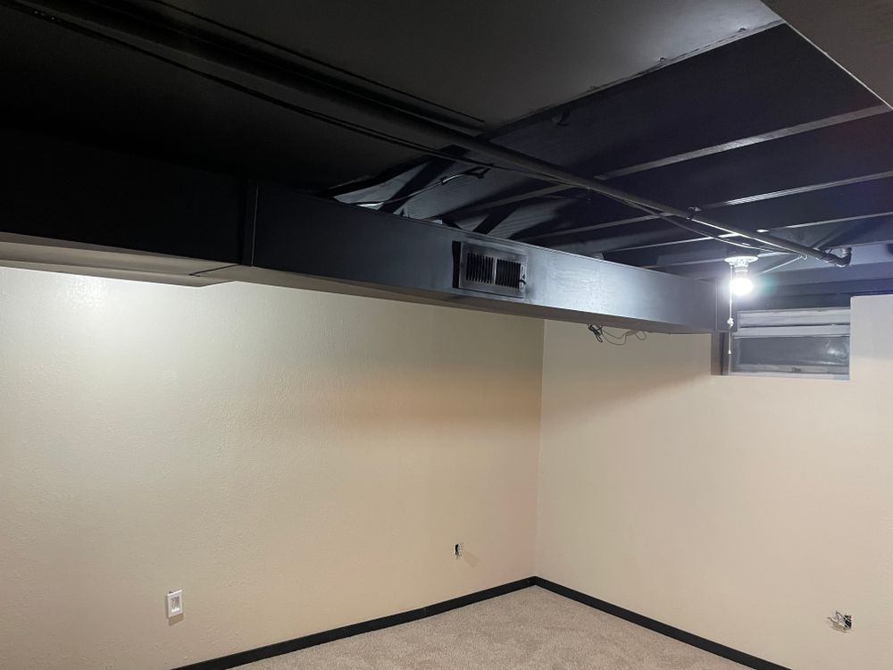 An empty basement with a black ceiling and a window