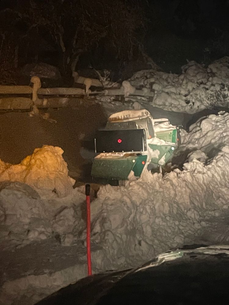 A mailbox is covered in snow in a parking lot at night