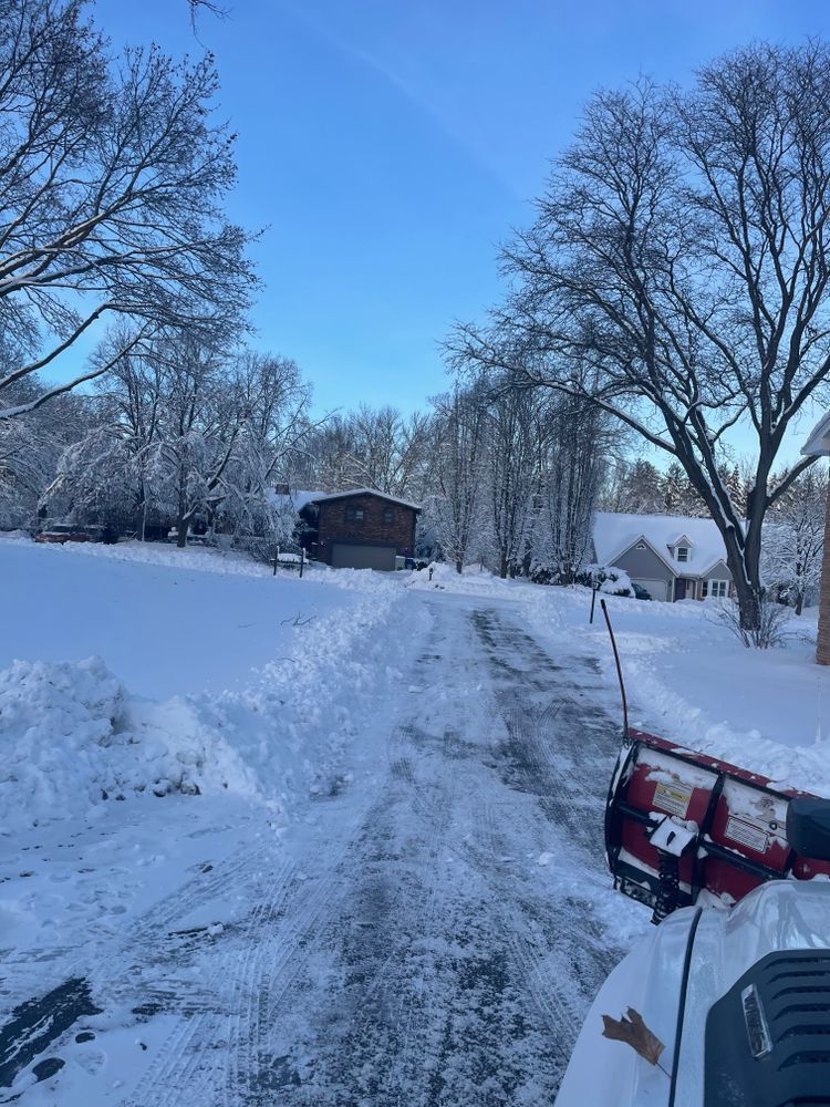 A snow plow is clearing a snow covered driveway
