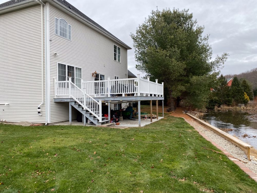 A large white house with a large deck next to a body of water