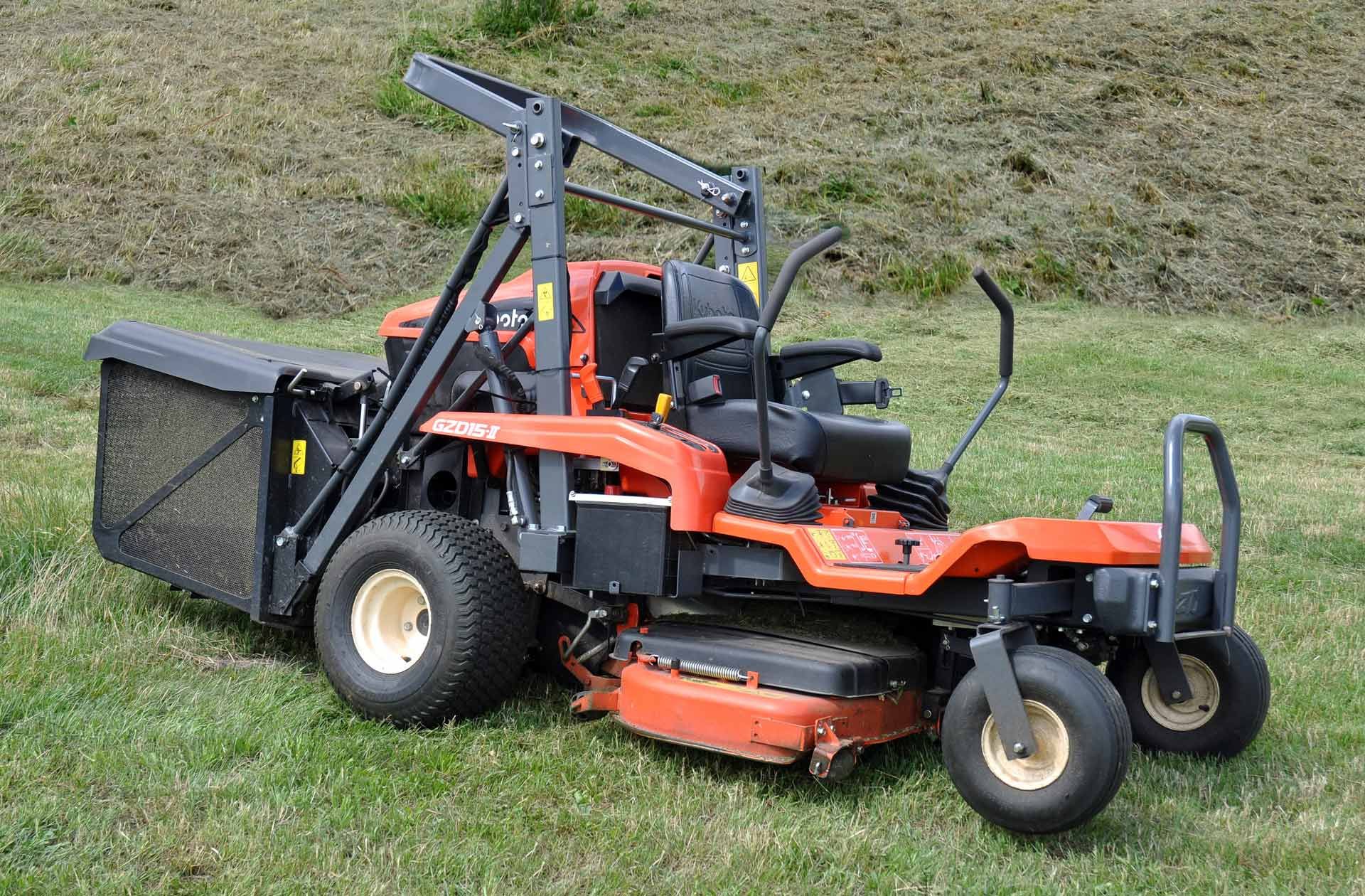 An orange lawn mower is parked in a grassy field