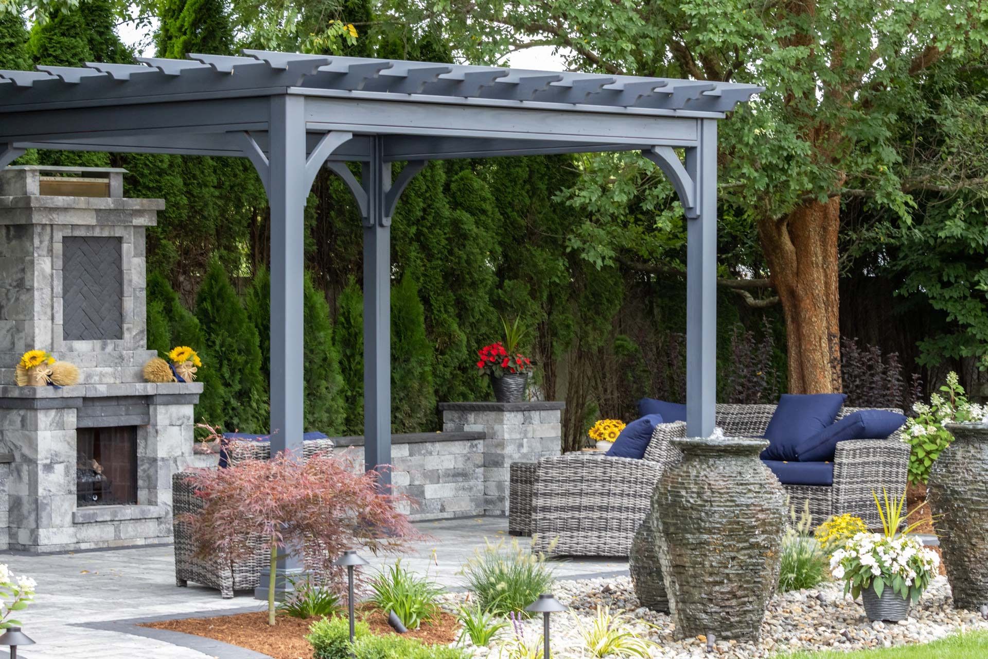 A patio with a pergola and a fireplace in the backyard.