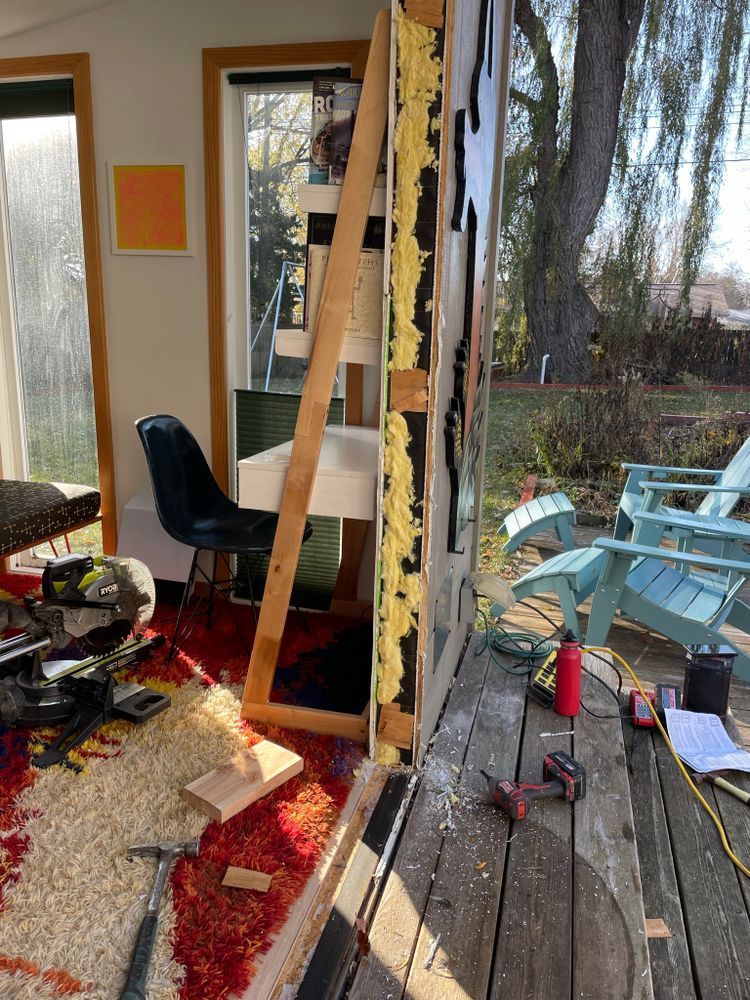 A room with a ladder , chairs , a table and a window