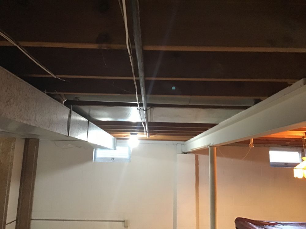 A basement with a wooden ceiling and a ceiling fan