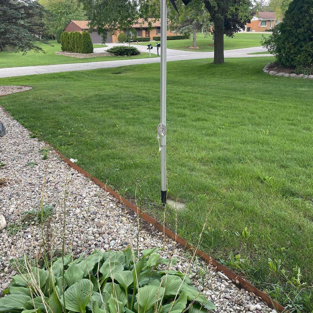 A flag pole in the middle of a lush green yard