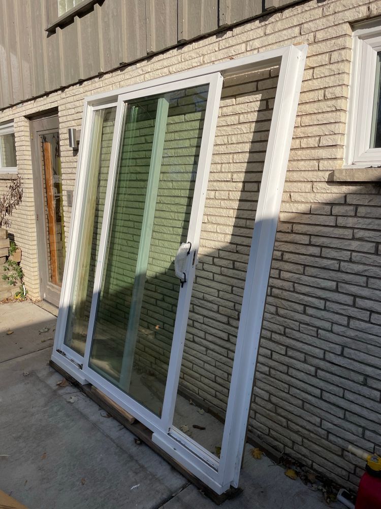 A white sliding glass door is sitting on the sidewalk in front of a brick building