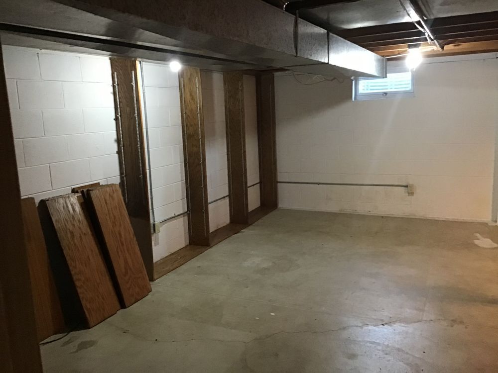 An empty basement with white walls and a concrete floor
