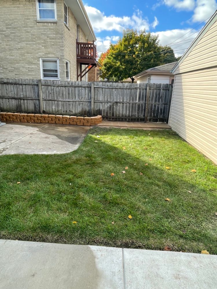 A backyard with a wooden fence and a house in the background