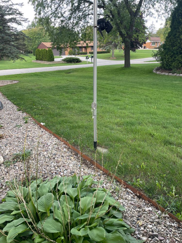 A flag pole is sitting in the middle of a lush green field