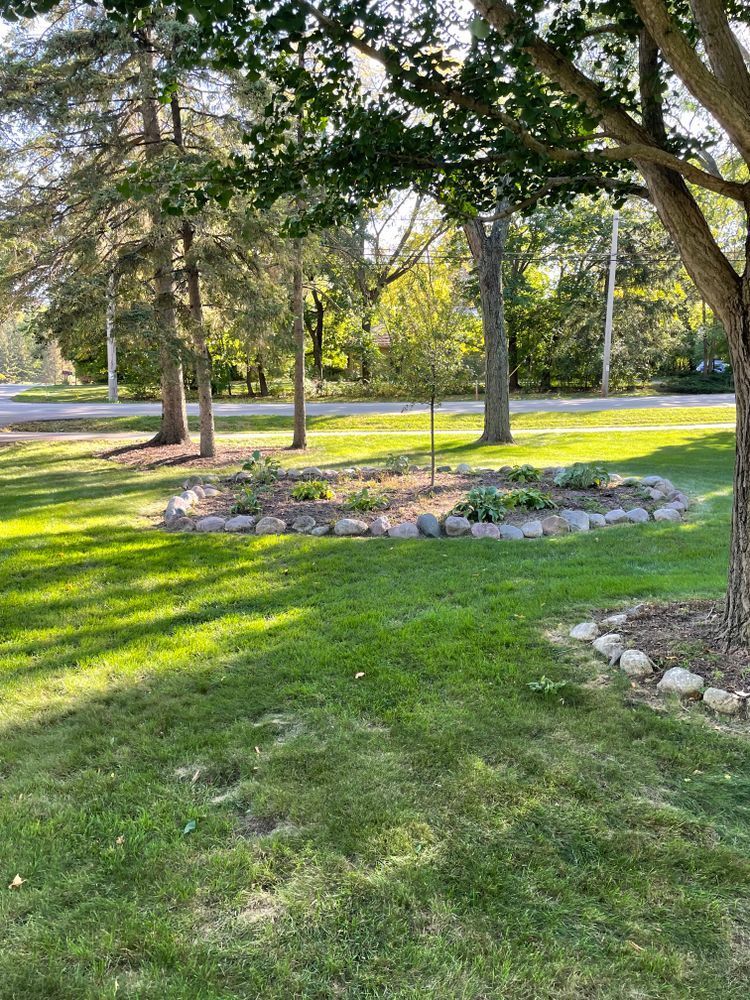 A lush green lawn with trees and rocks in the middle of it