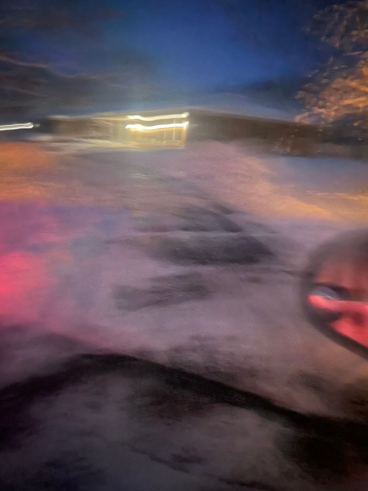 A blurry picture of a person riding a bike in the snow at night