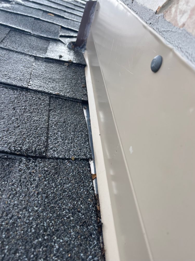 A close up of a gutter on a roof with shingles