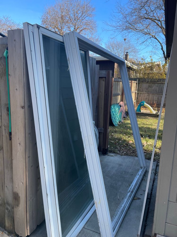 A bunch of windows are stacked on top of each other in a backyard