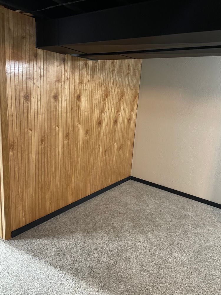 An empty basement with wood paneling and carpet