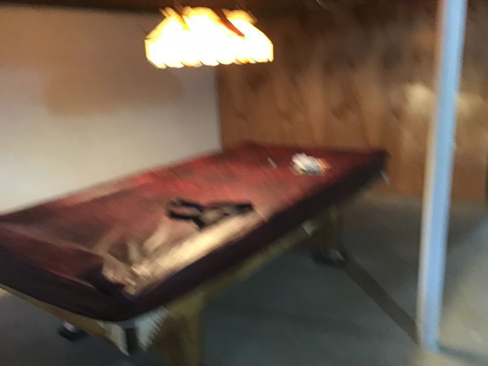 A pool table in a room with a lamp hanging from the ceiling