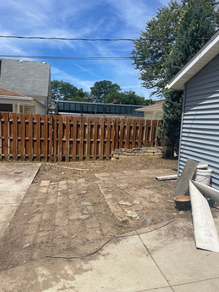 A backyard with a wooden fence and a house in the background